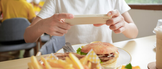 restaurant owner takes a picture of the food on the table with a smartphone to post on a website. Online food delivery, ordering service, influencer, review, social media, share, marketing, interest.