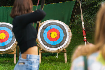 The girl shoots from a bow at a target in nature.