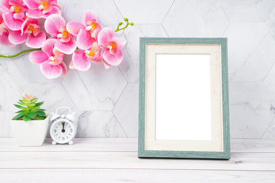 The Blank picture frame and alarm clock on wooden floor with copy space and clipping path for the inside.