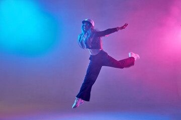 Obraz na płótnie Canvas a girl in dark clothes dances on a neon background in smoke, modern dance
