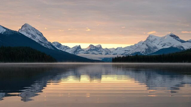 Scenery of sunrise over mountain range and water reflection in Maligne Lake at Jasper national park