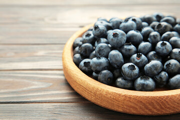 Fresh blueberry in wooden bowl on brown background. Concept of healthy and dieting eating