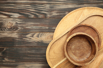 Different wooden plate and trays on brown background. Space for text