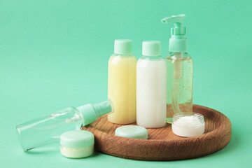 Travel cosmetic bottles with tray on mint background. Minimalist bodycare beauty products for vacation or journey. Top view. Copyspace.