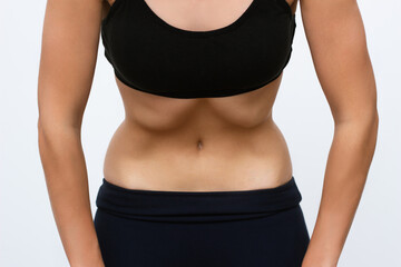 A young fitness woman in a sports black closes does a vacuum abdominal abdomen muscles on a light...