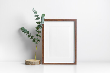 Portrait wooden frame mockup in white interior with trendy botanical decor, copy space for artwork...