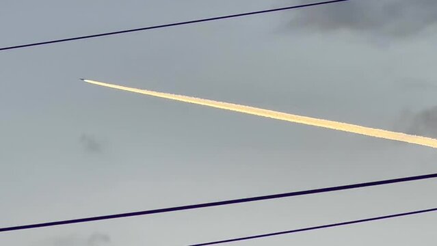 Energizing Twilight: Zoom on An Plane Trail in the Symphony of Light, Shadow and Power Interplay Across the Urban Landscape