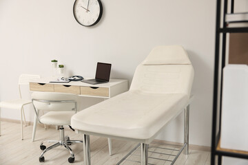 Modern medical office with doctor's workplace and examination table in clinic