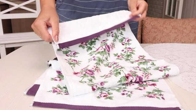 The woman makes a review of the purchase. Lays terry towels on the table. Close-up.