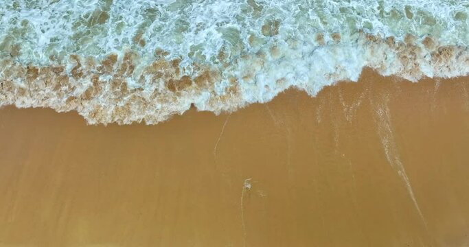 White foam waves roll in beautiful wrinkles as they hit the sandy beach. .and the sun glimmering off the foam creates a stunning sight..White foam creates beautiful streaks on the green sea..
