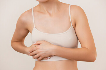 a young woman in beige underwear is experiencing severe acute pain in her right side, holding her...
