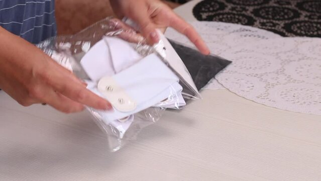A woman unpacked a white belt. With a bow buckle. He takes out from packaging and considers. Close-up.