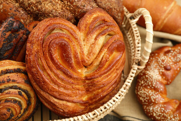 Fototapeta premium Wicker basket with different tasty freshly baked pastries on table, closeup