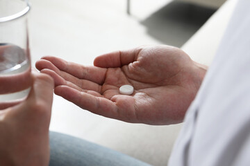 Man with glass of water and pill on blurred background, closeup