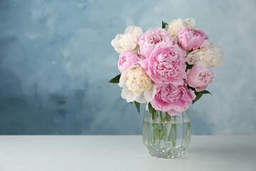 Beautiful peonies in glass vase on white table. Space for text - obrazy, fototapety, plakaty