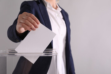 Woman putting her vote into ballot box on light grey background, closeup. Space for text - obrazy, fototapety, plakaty