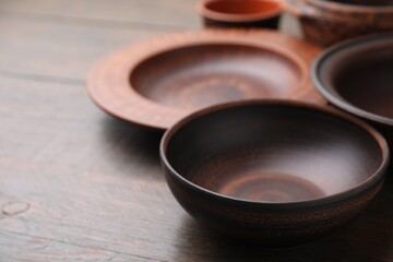 Set of clay dishes on wooden table, space for text. Cooking utensils