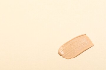Smear of skin foundation on beige background, top view. Space for text