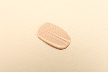 Smear of skin foundation on beige background, top view