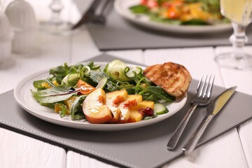 Delicious salad with peach slices served on white wooden table