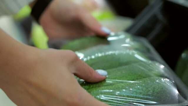 Close-up of a woman in a vegetable supermarket choosing cucumbers in a package