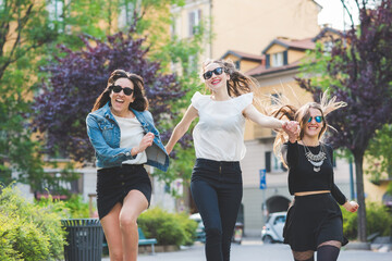 Three young women millennials outdoor in the city running and jumping