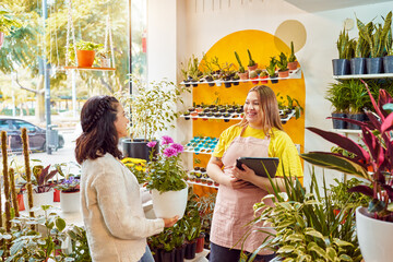 portrait caucasian female employee owner of a plant store assisting a customer holding digital tablet