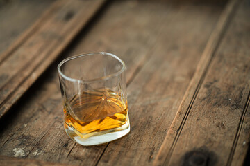 Glass of wiski or scotch on wooden barrel with blurred background