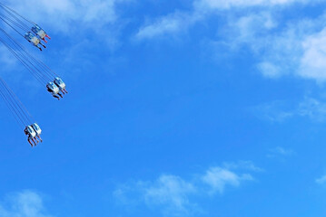 A fairground attraction under the blue sky.  Concept of emotion, adventure and elevation. Space for text.
