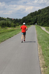 A runner in a red T-shirt, actively spends time in our air, in beautiful natural circumstances