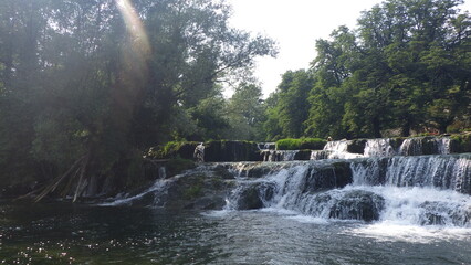 Waterfall on the river with stones in sunny weather
