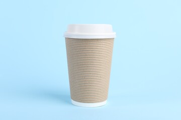 Paper cup with plastic lid on light blue background. Coffee to go