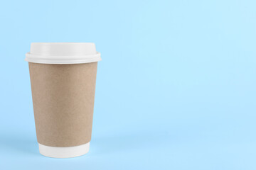 Paper cup with plastic lid on light blue background, space for text. Coffee to go