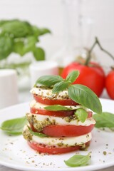 Plate of stacked Caprese salad with pesto sauce on table, closeup
