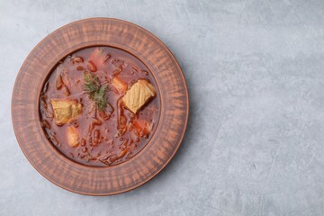 Obraz na płótnie Canvas Bowl of delicious borscht on light grey table, top view. Space for text