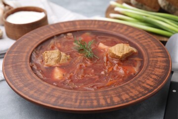 Bowl of delicious borscht on light grey table, closeup