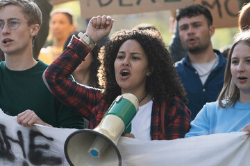 Student Activist Leading Protest with Megaphone - A close-up of a young curly-haired woman leading...