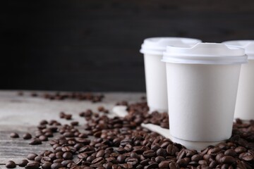Coffee to go. Paper cups and roasted beans on table, closeup. Space for text