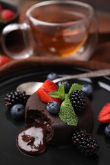 Delicious chocolate fondant, berries and mint on plate, closeup