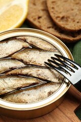 Canned sprats and fork on board, closeup