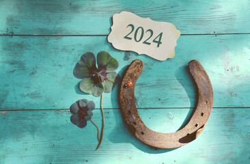 Horseshoe with lucky clover - 2024 greeting card horseshoe on wooden background - happy new year...
