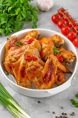 Baked chicken wings served with sweet chili sauce and fresh herbs. Selective focus.