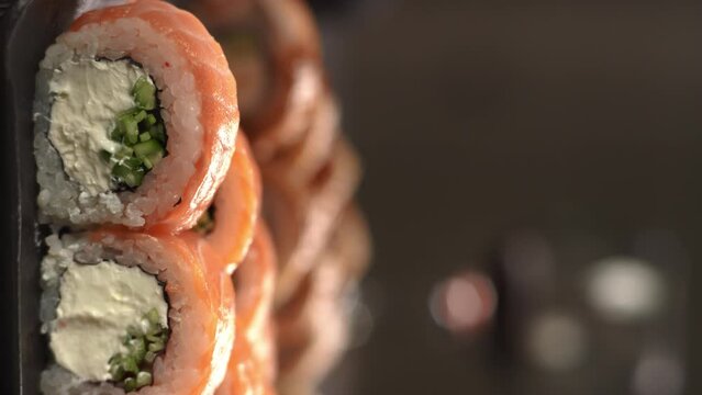 Eating sushi with chopsticks close up, food takeout, salmon sushi rolls on plate