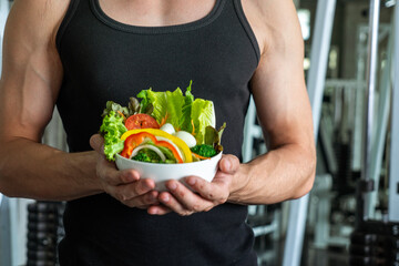 Caucasian man exercising muscle building holding wooden bowl of vegetable salad healthy eating in...