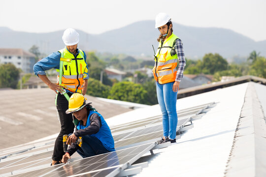 Electrical engineering man using electric hand drill to Installing Solar Cell panels on Roof. Solar energy clean and green alternative energy concept