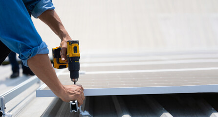 Close up hand worker. Electrical engineering man using electric hand drill to Installing Solar Cell panels on Roof. Solar energy clean and green alternative energy concept