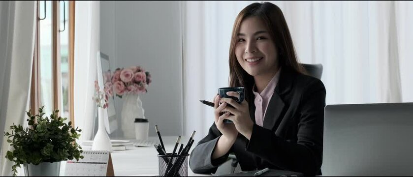 Slow motion shot of attractive businesswoman drinking tea, enjoying her leisure time during her work break