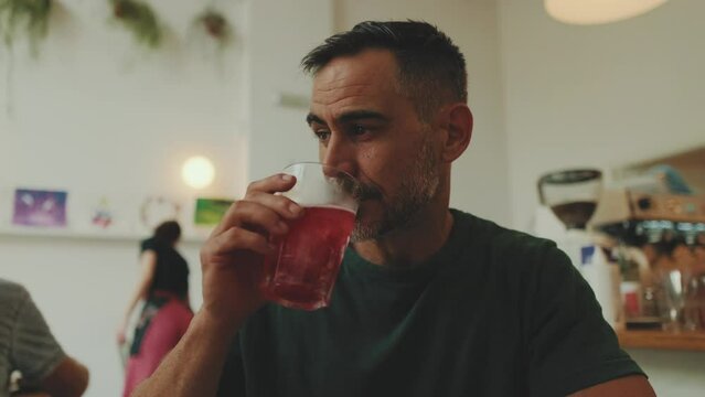 Close up, middle-aged man sitting in cafe drinking cold drink
