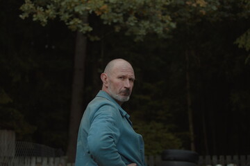 Fototapeta premium mature man in work clothes on the background of the forest looks at the camera