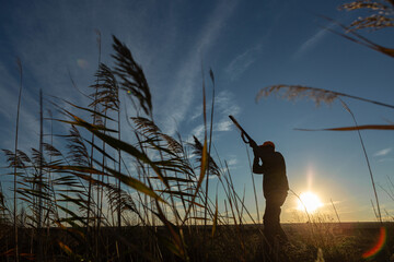 Fototapeta premium Hunter aiming with rifle while standing against sky